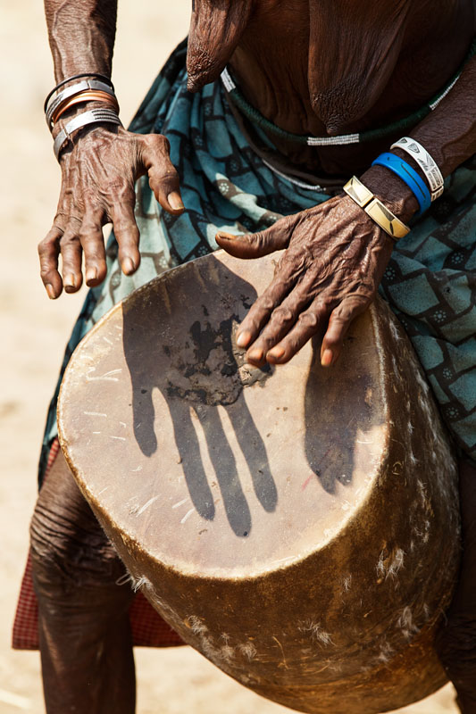  Old woman from the Muchimba or Himba tribe, playing the drum during the 2 day celebration of Mufinco (where they celebrate the change from girl to woman)    Angola